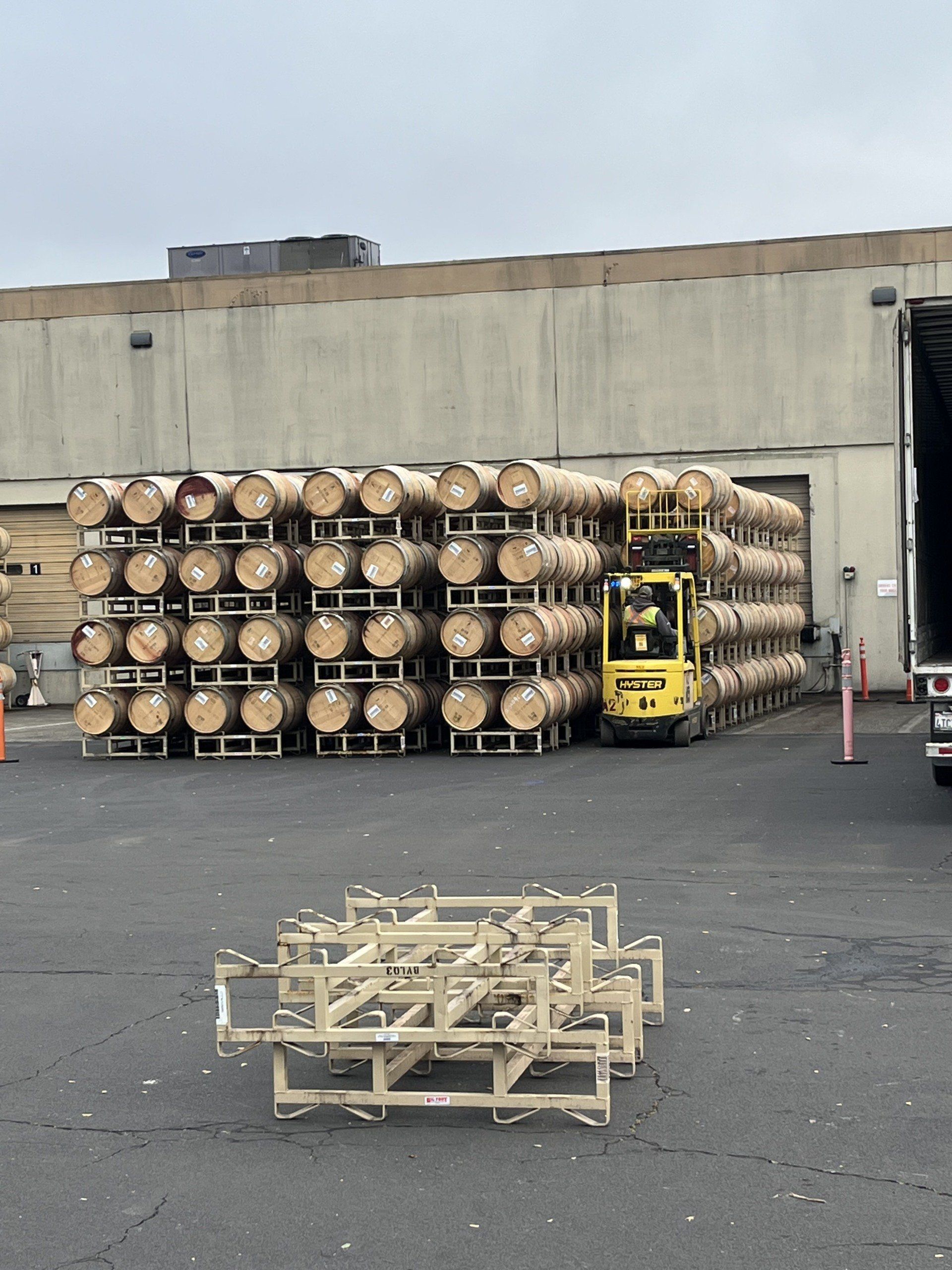 A forklift is loading barrels into a truck