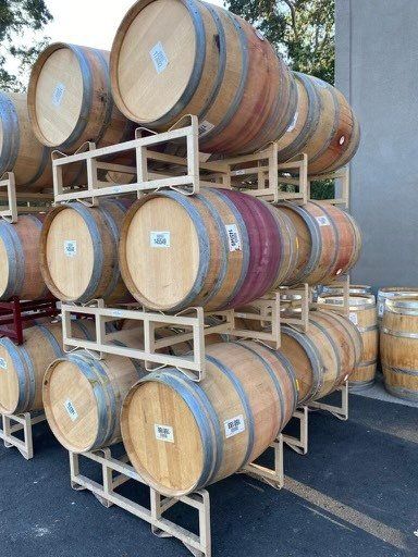 A bunch of wooden wine barrels are stacked on top of each other.