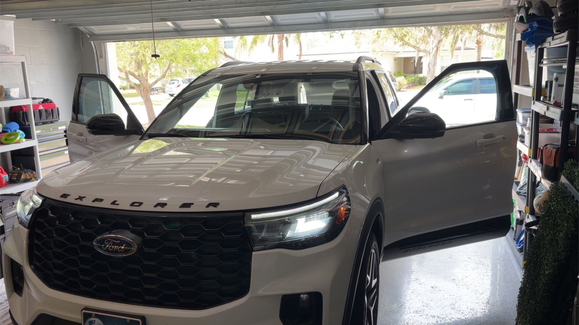 A white Ford Explorer with both front doors open, parked inside a garage.