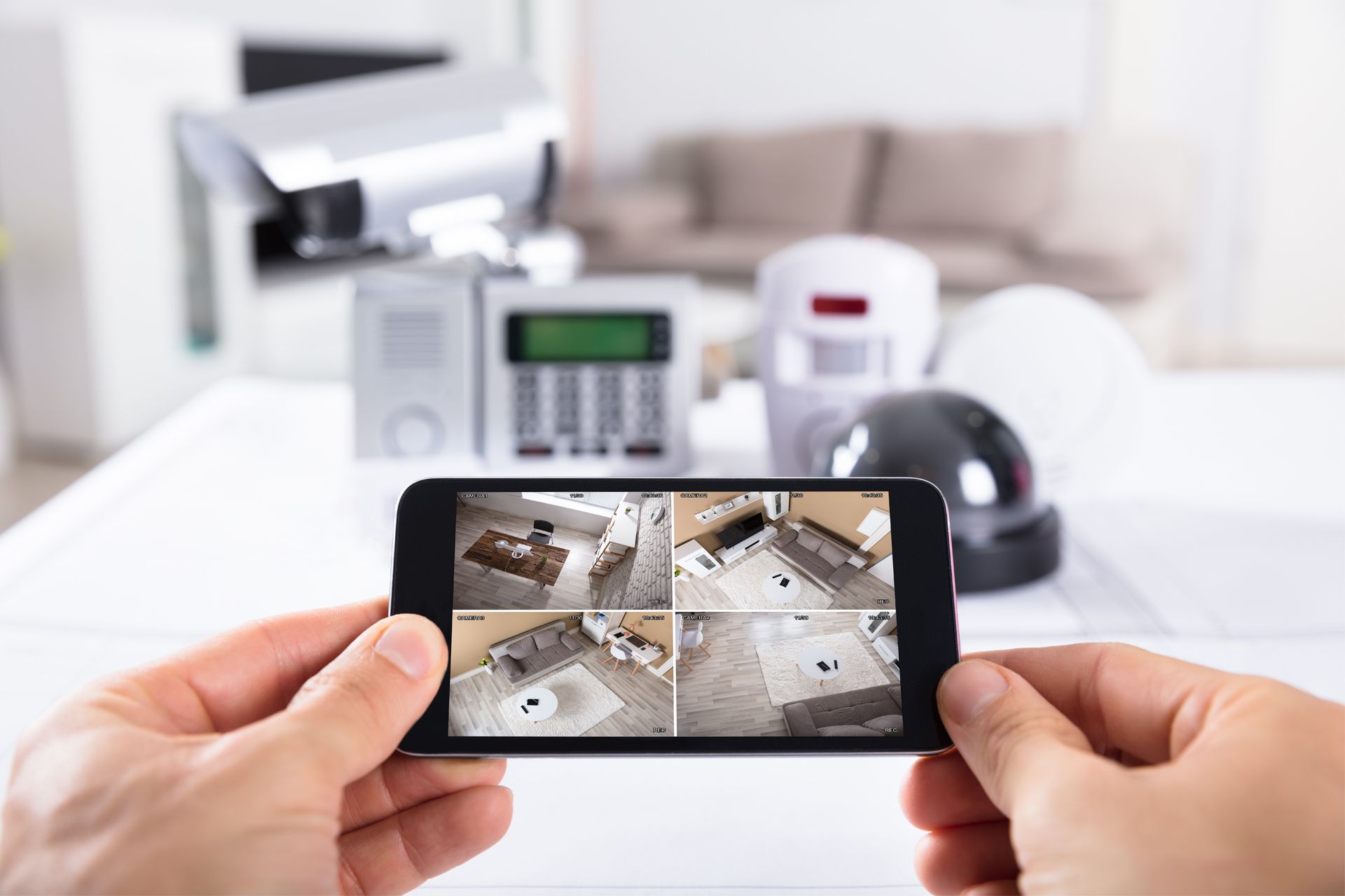 Hands holding a smartphone displaying live security camera footage