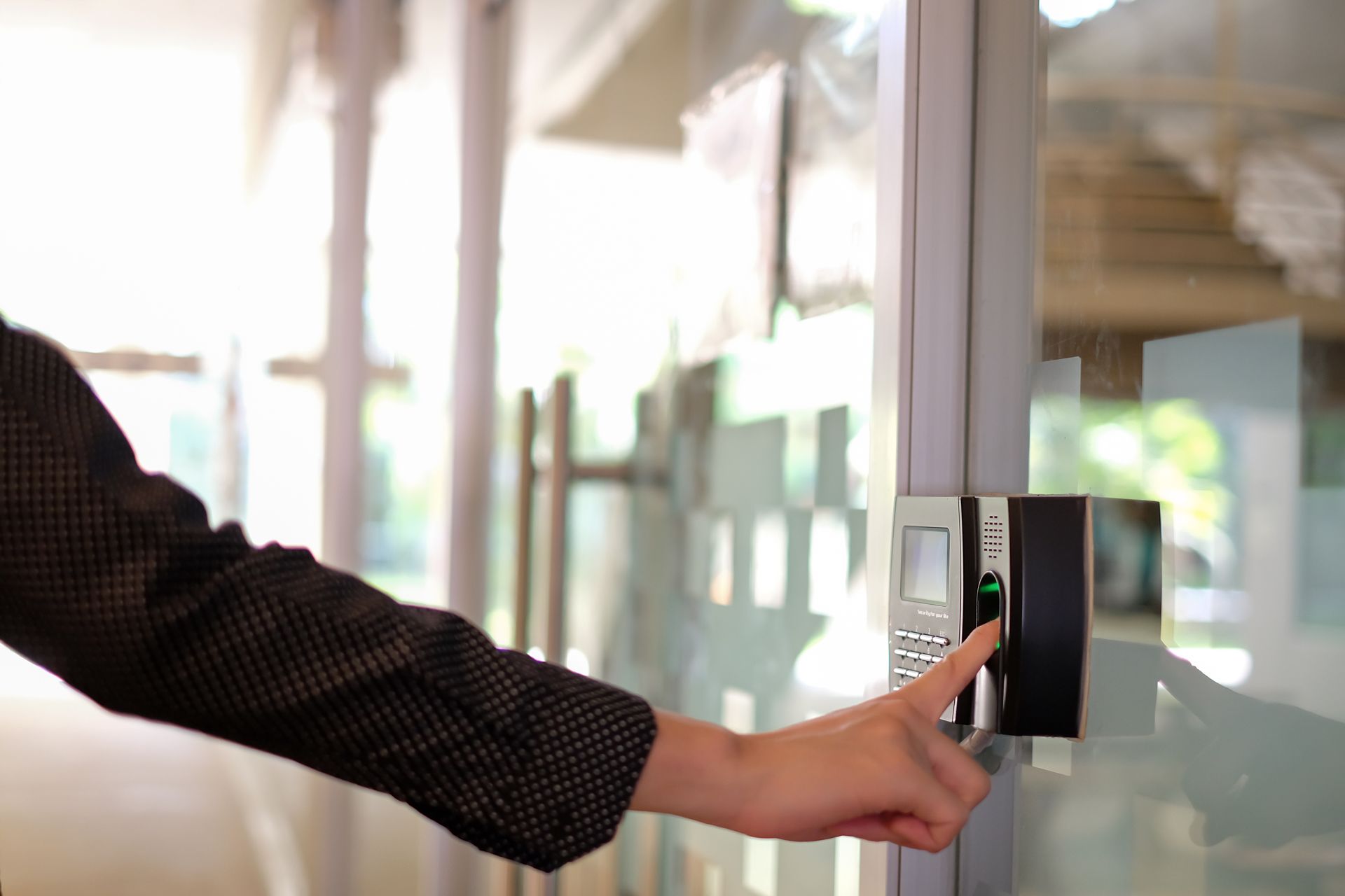 A person's hand pressing a finger on a biometric scanner