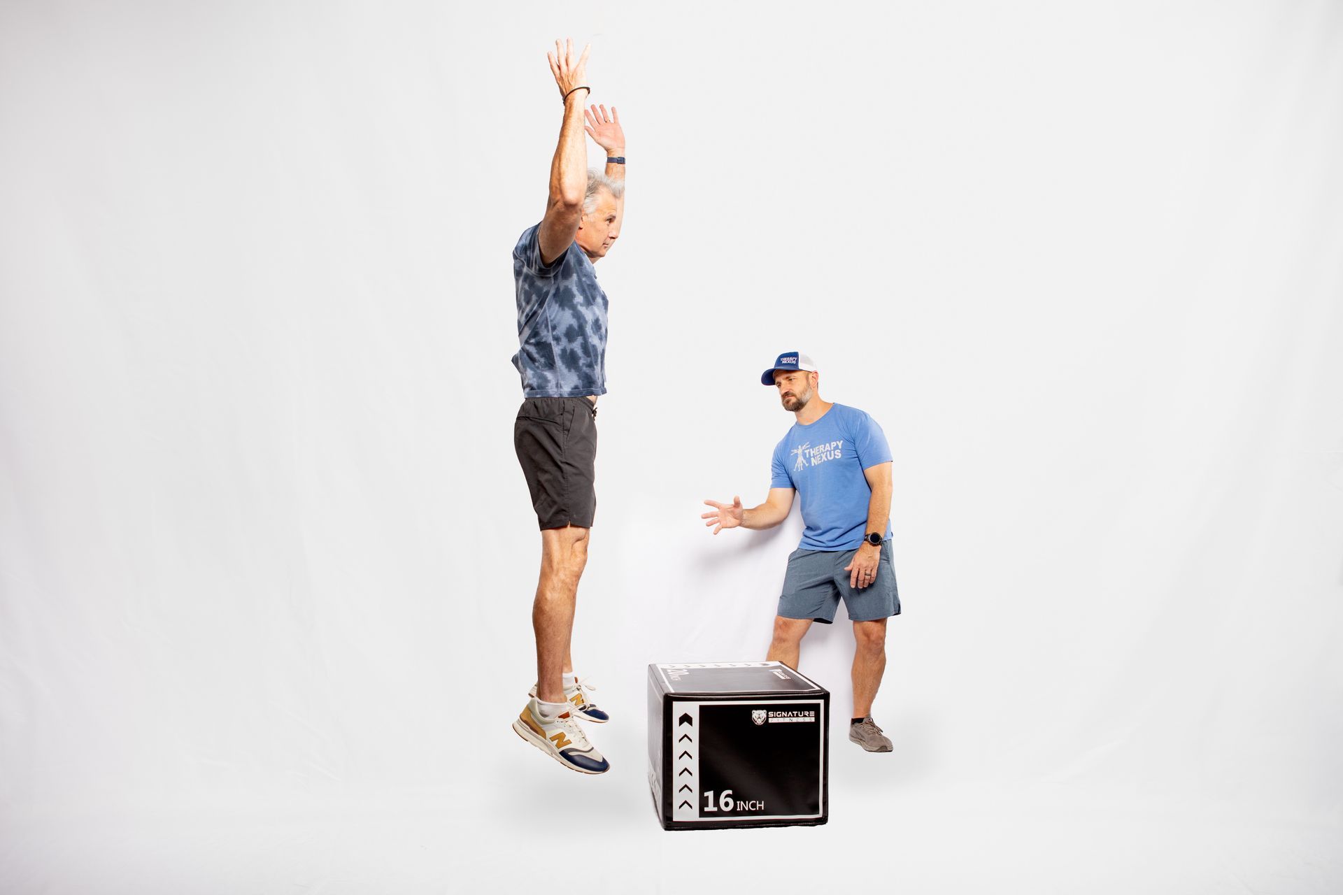 Man jumping over a box with a trainer. White background.