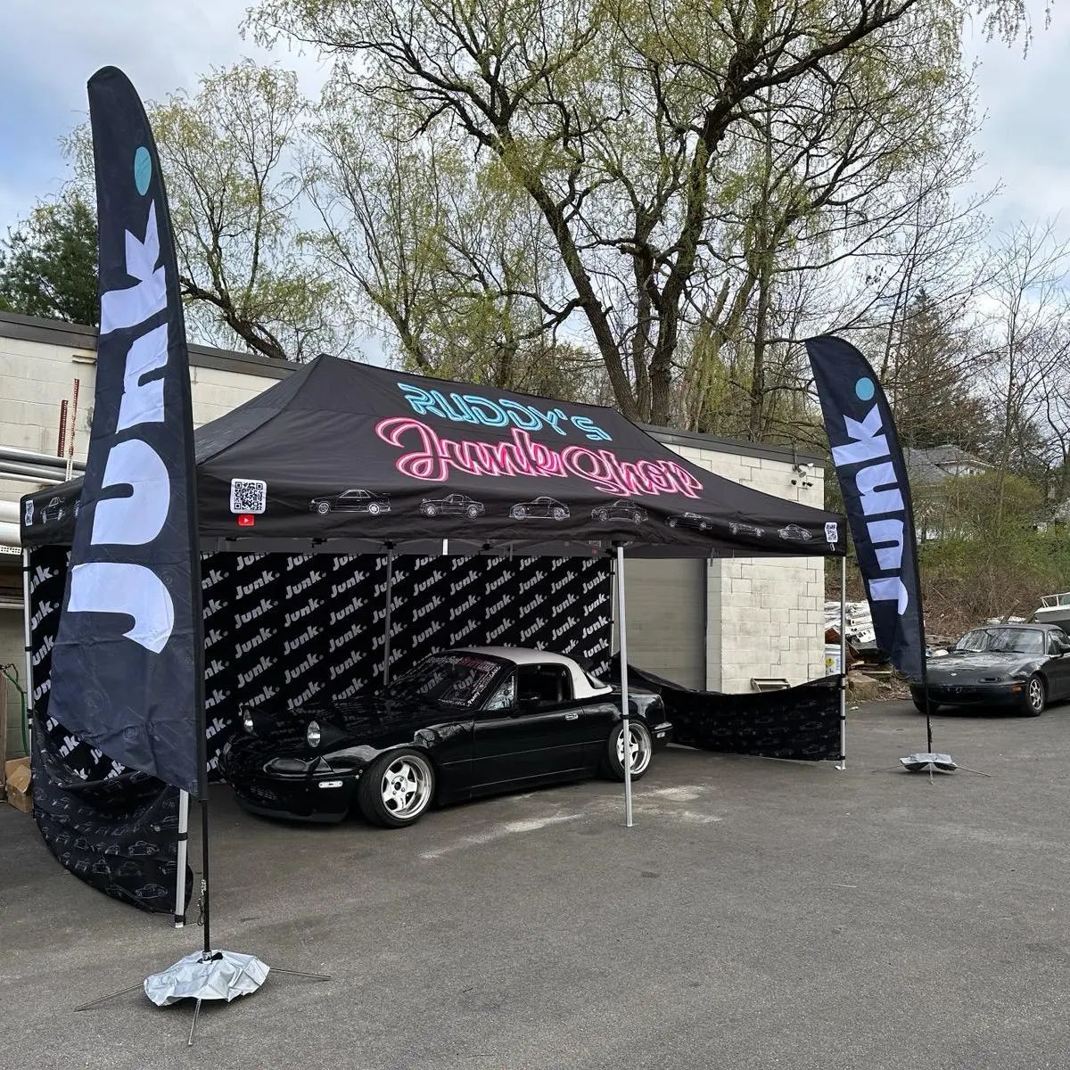 A car is parked under a tent that says junk