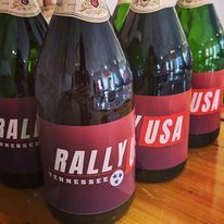 A row of bottles of beer are sitting on a wooden table.