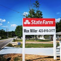 A state farm sign is sitting on the side of a road.