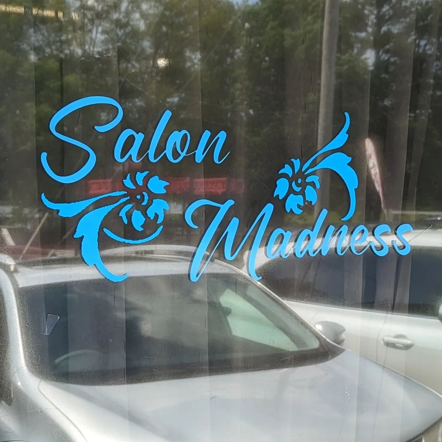 A car is parked in front of a window that says salon madness