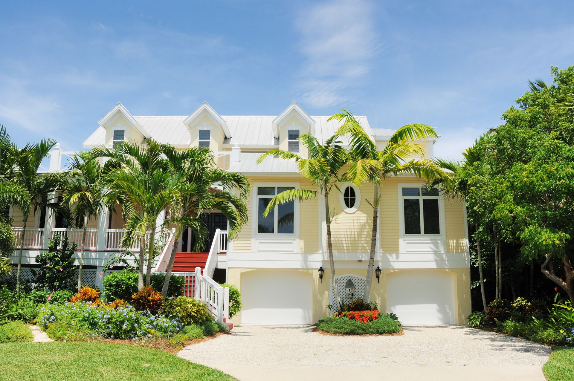 A large house with two garages and palm trees in front of it