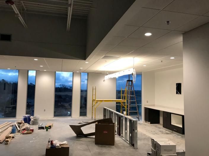An unfinished room with windows, a metal scaffold, construction materials, and a counter under construction.