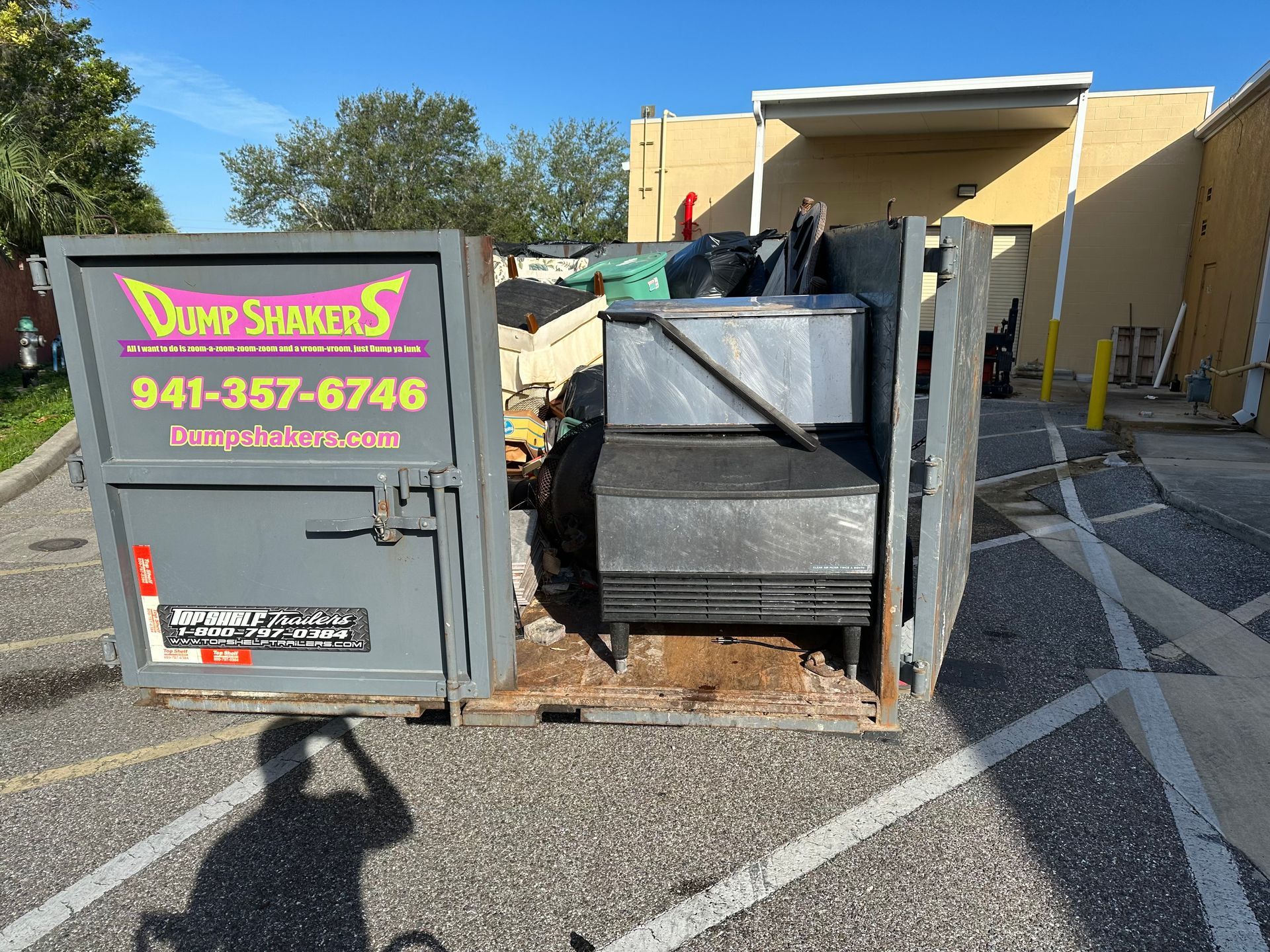 A dumpster is parked in a parking lot in front of a building.