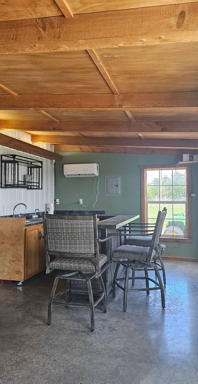 There is a bar and chairs in the middle of the wine tasting room.