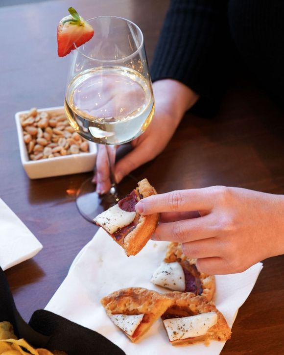 una persona tiene in mano un piatto di cibo e un bicchiere di vino