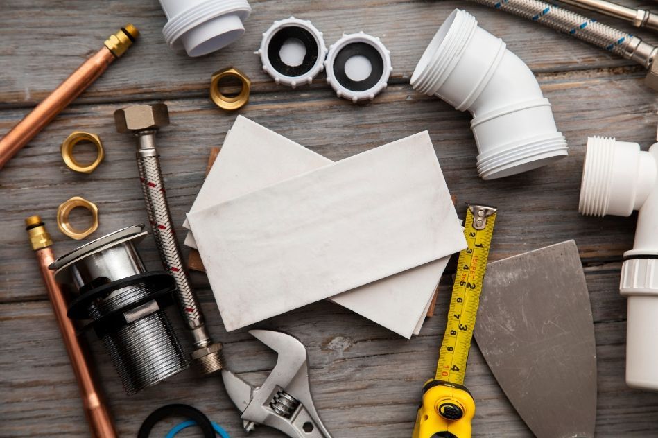 A wooden table topped with plumbing tools and a business card.