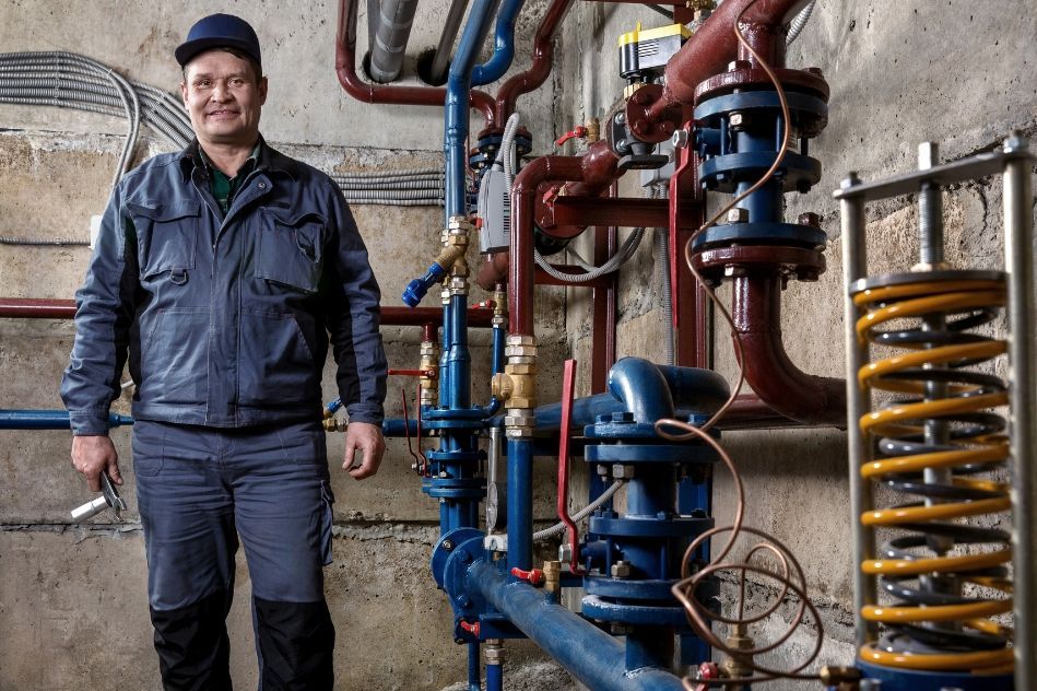 A man is standing in front of a bunch of pipes and valves.