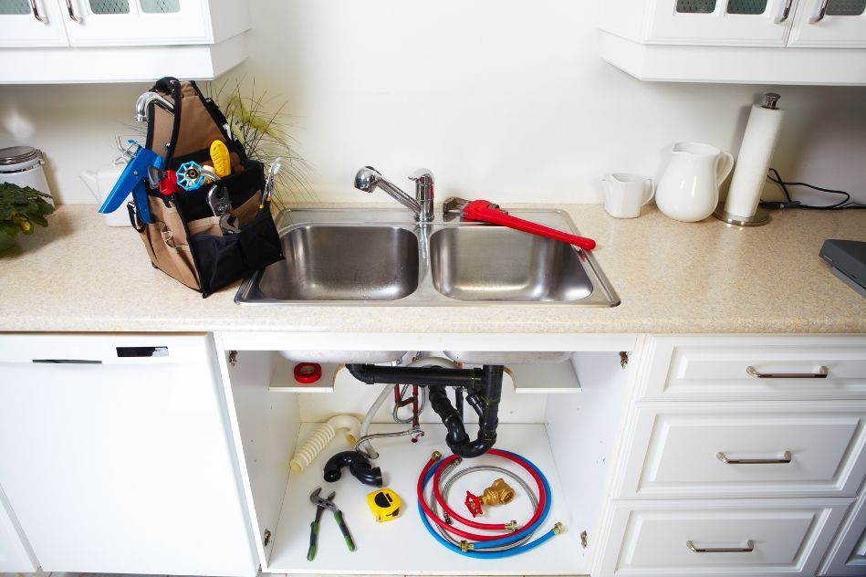 A kitchen sink with a bag of tools underneath it.