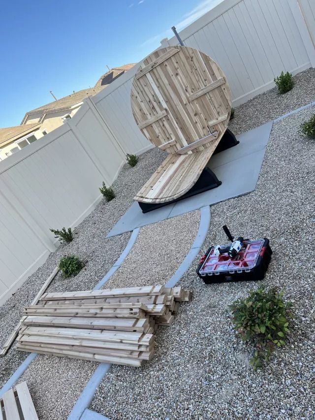 A large wooden structure resembling a target in a gravel backyard with a small remote-controlled vehicle.