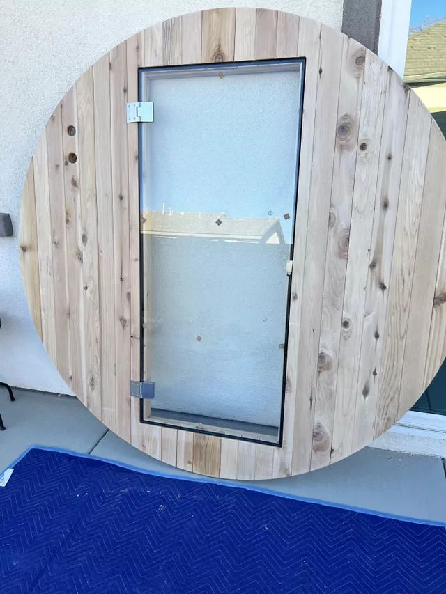 Circular wooden structure with a rectangular glass door.