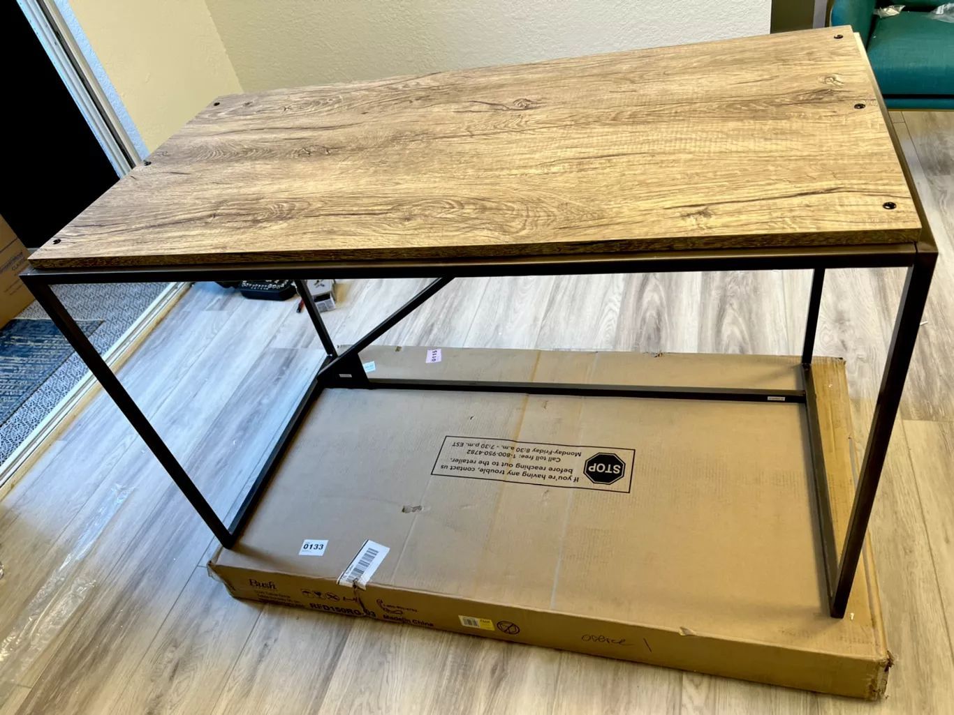 Coffee table with a brown wood top and a black metal frame, sitting on a cardboard box.