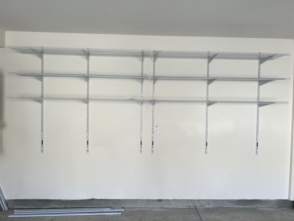 Garage wall with three tiers of installed wire shelving.