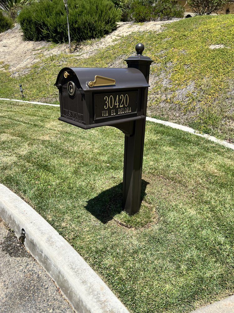 Brown mailbox with address 30420 on a post in front of a grassy hill.