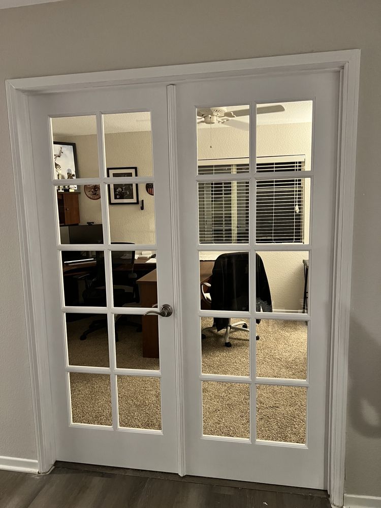 White French doors leading into a room with office furniture visible through the glass panes.