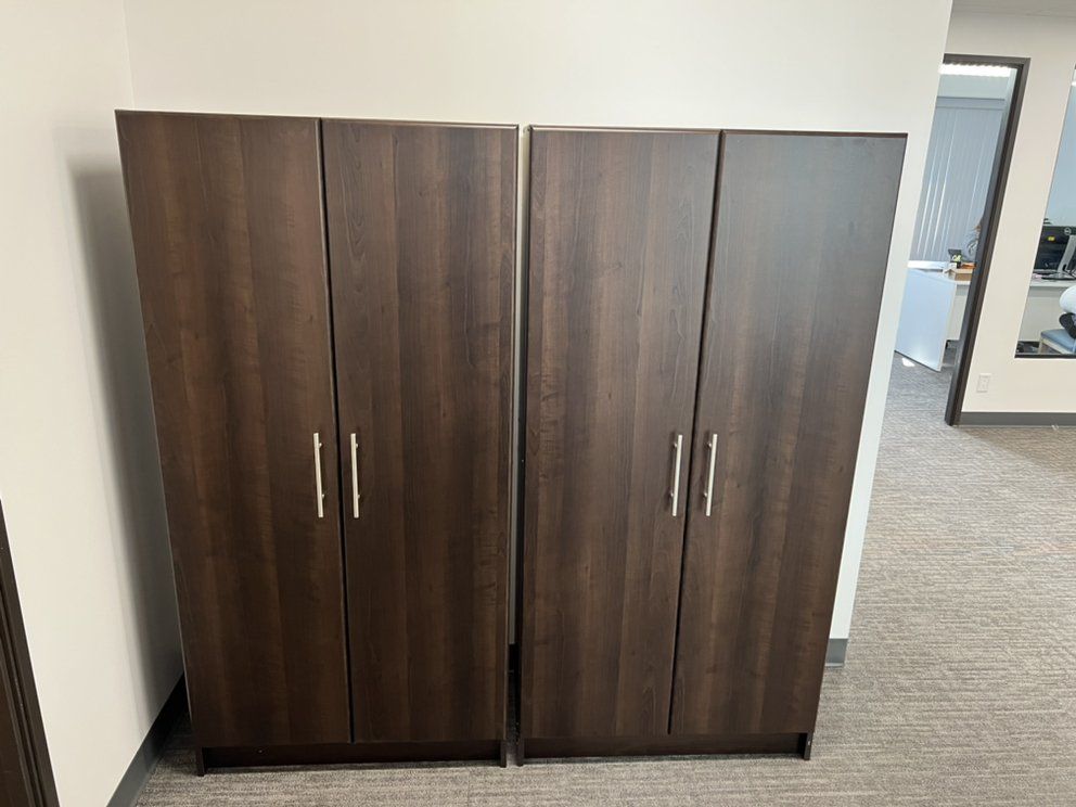 Two dark brown wooden cabinets with silver handles stand side by side in a room.
