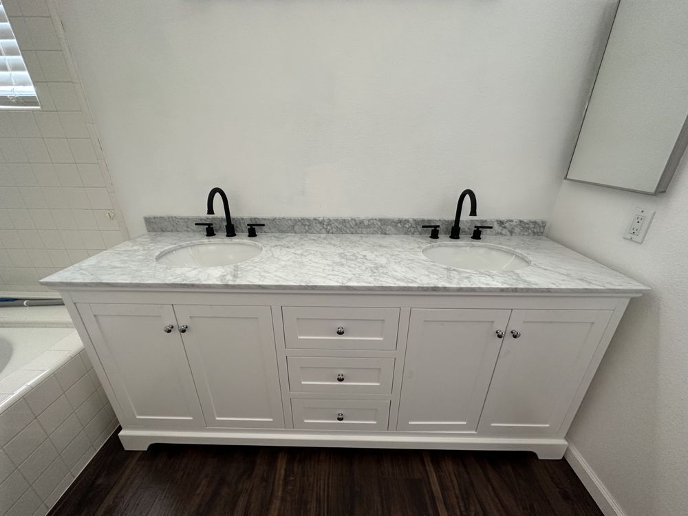 White double sink vanity with black faucets and marble countertop in a bathroom.