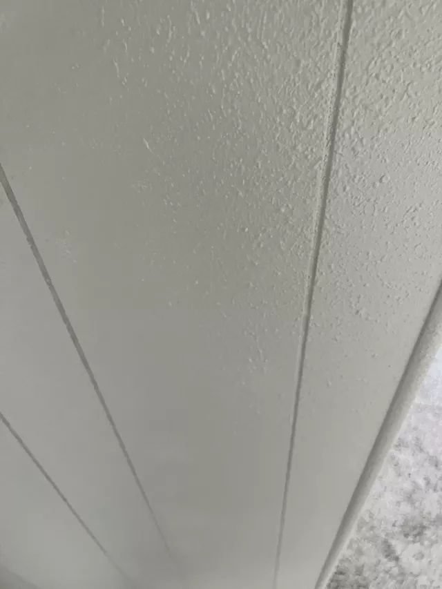 Close-up of a painted, light-colored wooden wall with vertical panel lines.