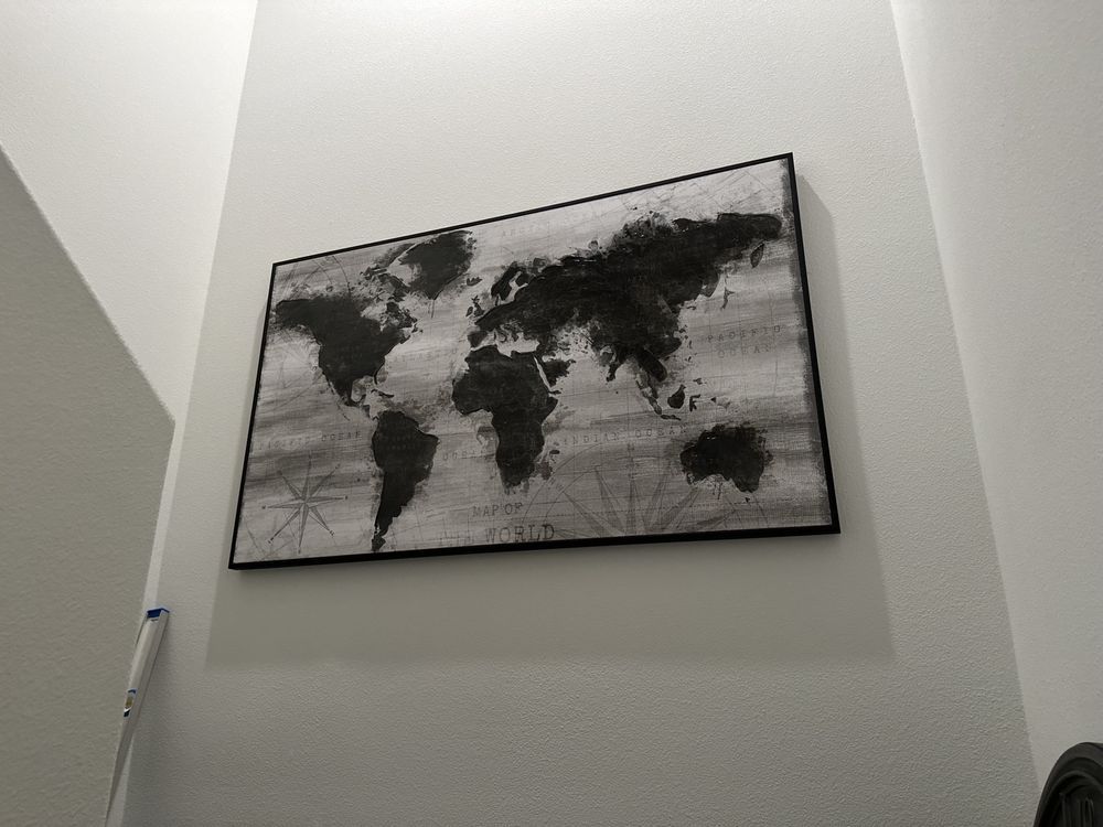 Black and white world map art framed on a white wall.