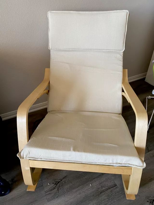 Cream-cushioned rocking chair with light wood frame; against a light wall.