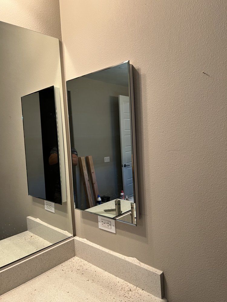 Bathroom mirrors on wall above countertop. One mirror is open, revealing items inside.
