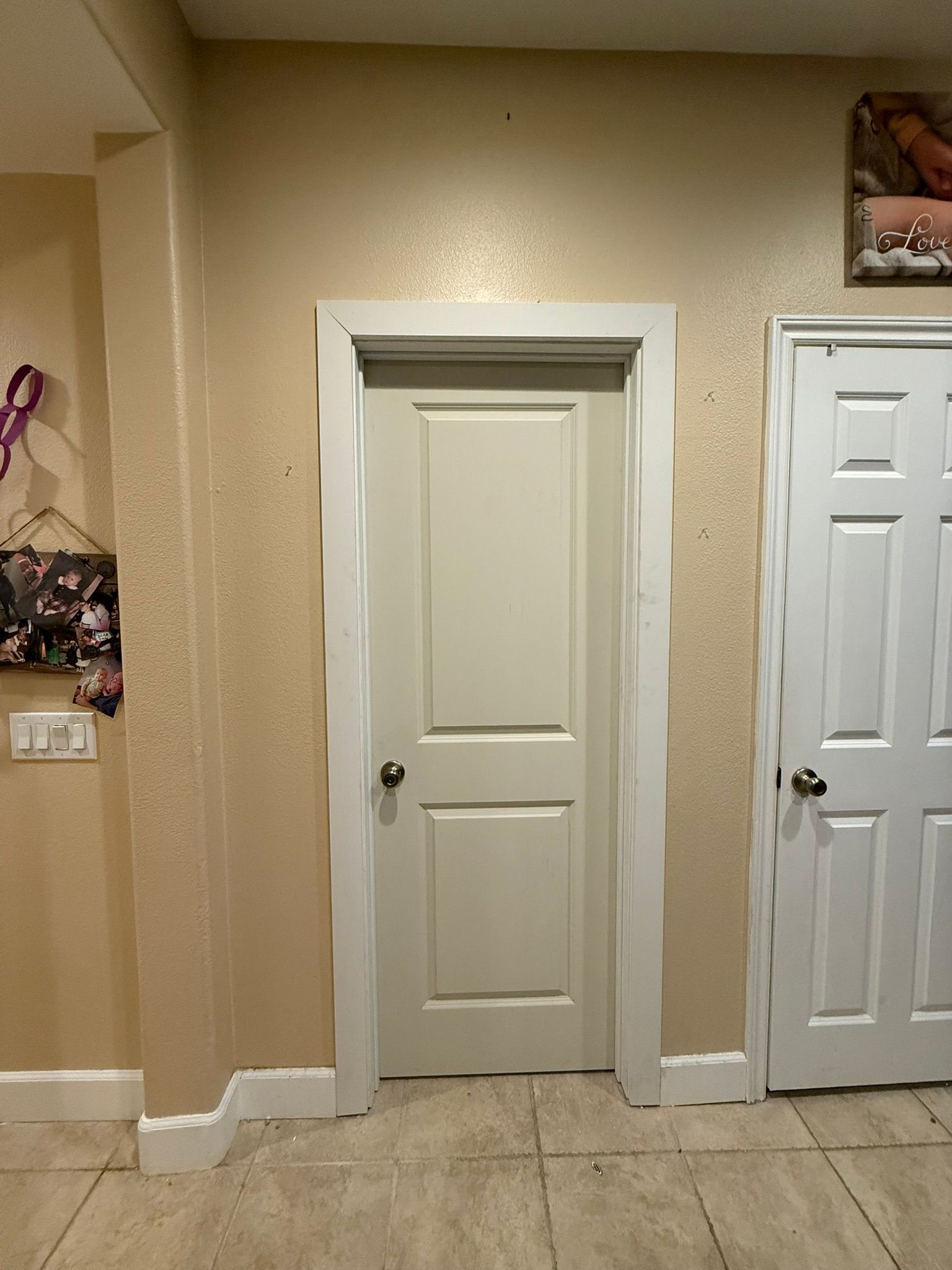 A hallway with a closed beige door and white trim. Adjacent is a white door. The walls are beige.