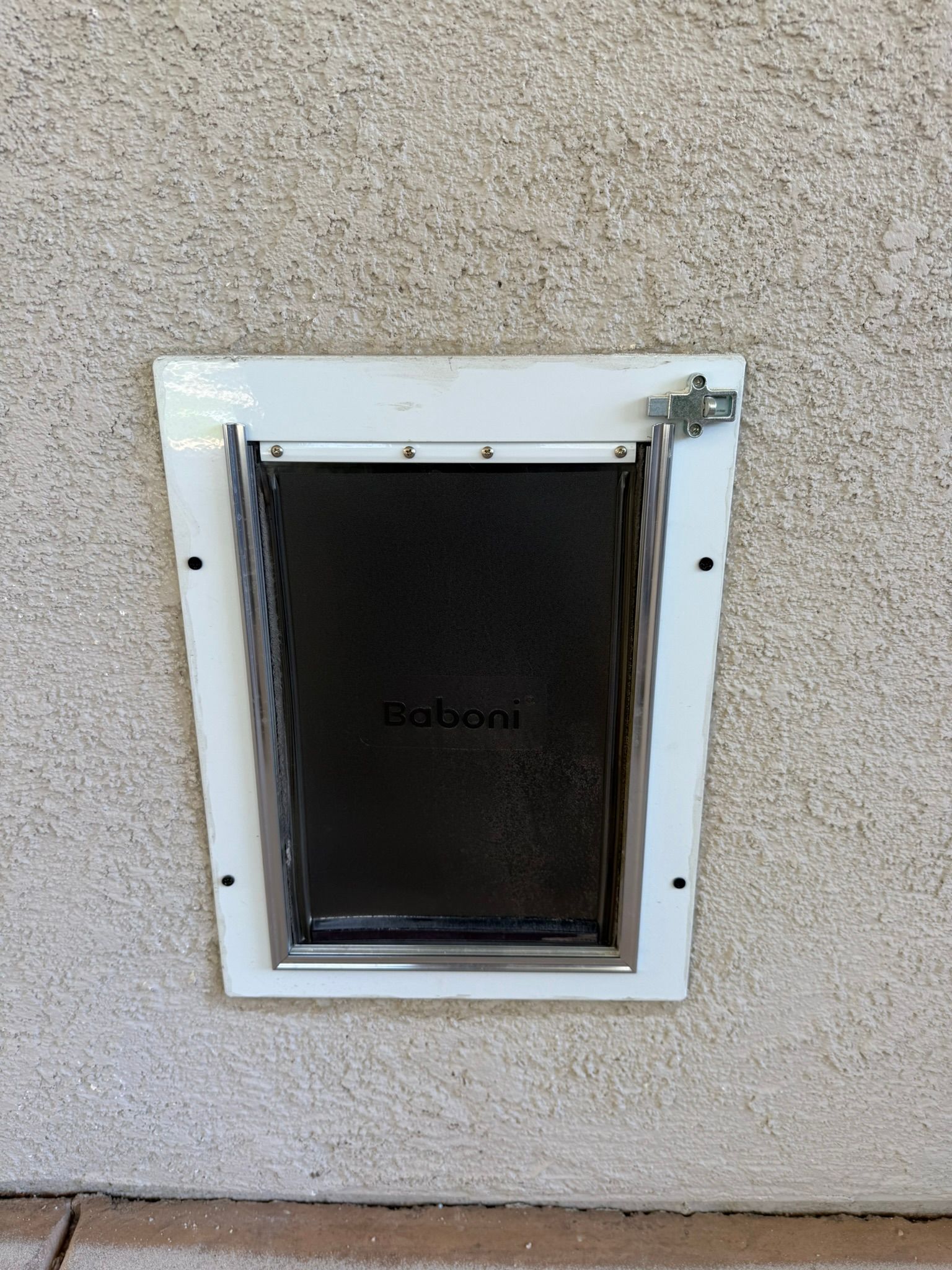 White pet door installed in a stucco wall.