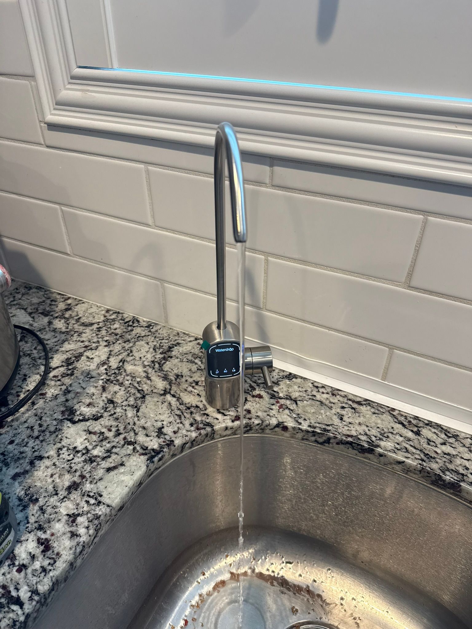 A kitchen sink with running water, a stainless steel faucet, and a granite countertop.
