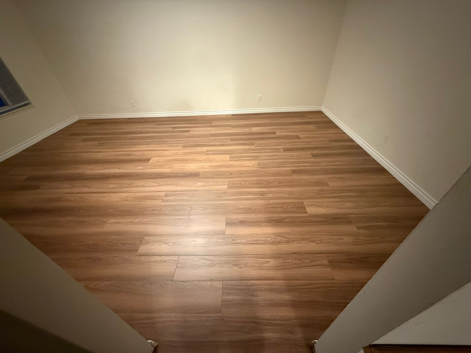 Empty room with wood-look flooring and off-white walls.