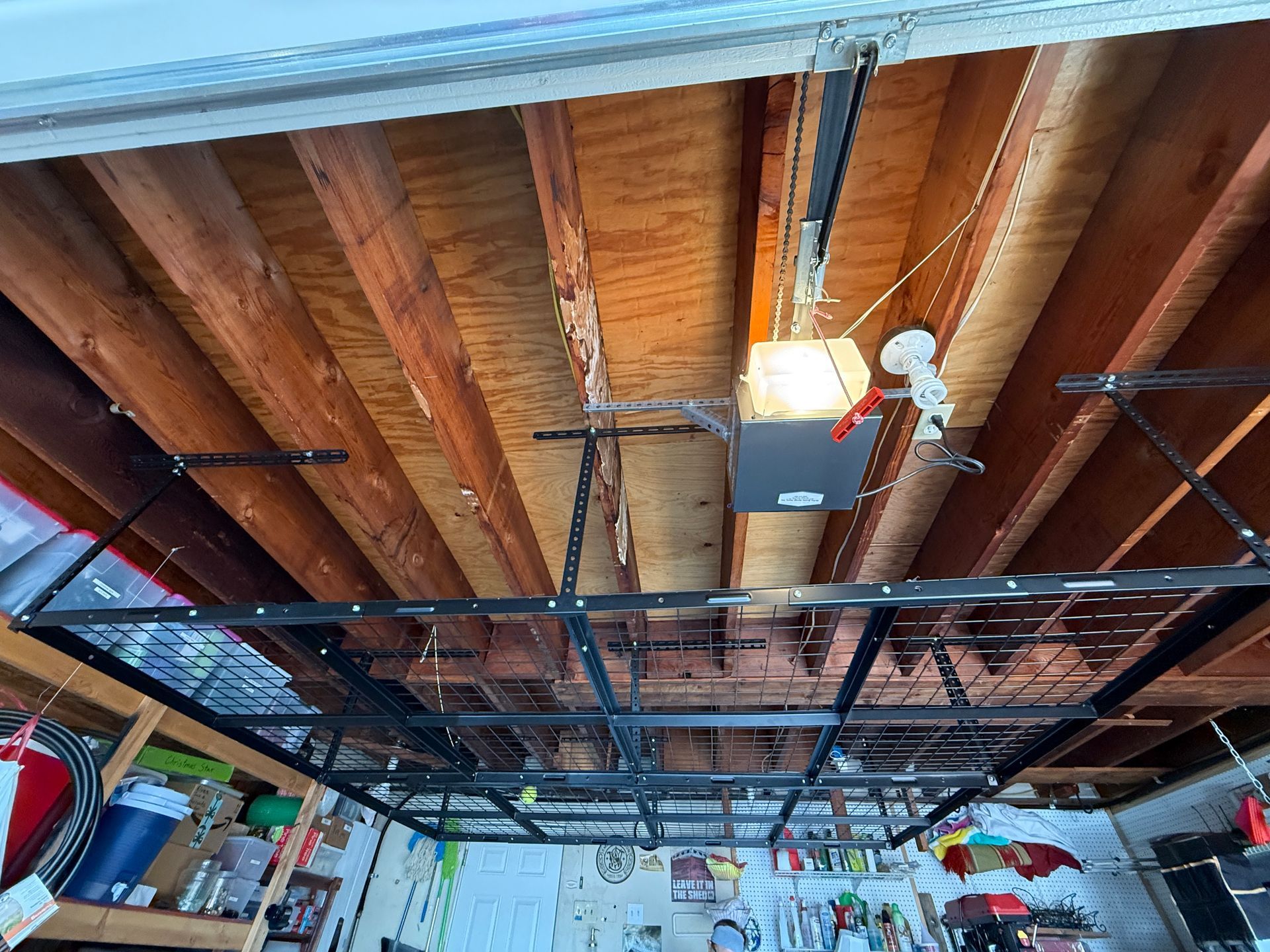 Overhead garage storage rack suspended from wooden ceiling beams.