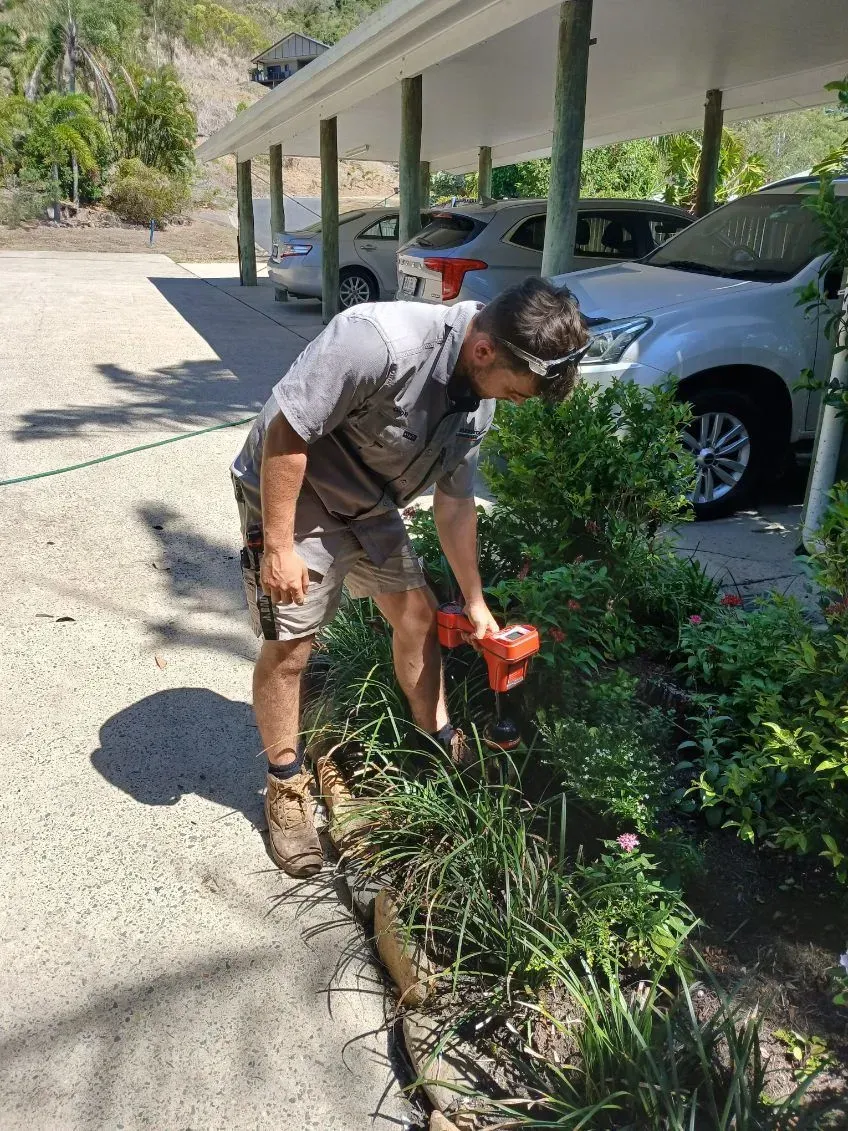 A Person in A Gray Shirt and Shorts Trims Garden — Dunnrite Plumbing Services in Airlie Beach, QLD