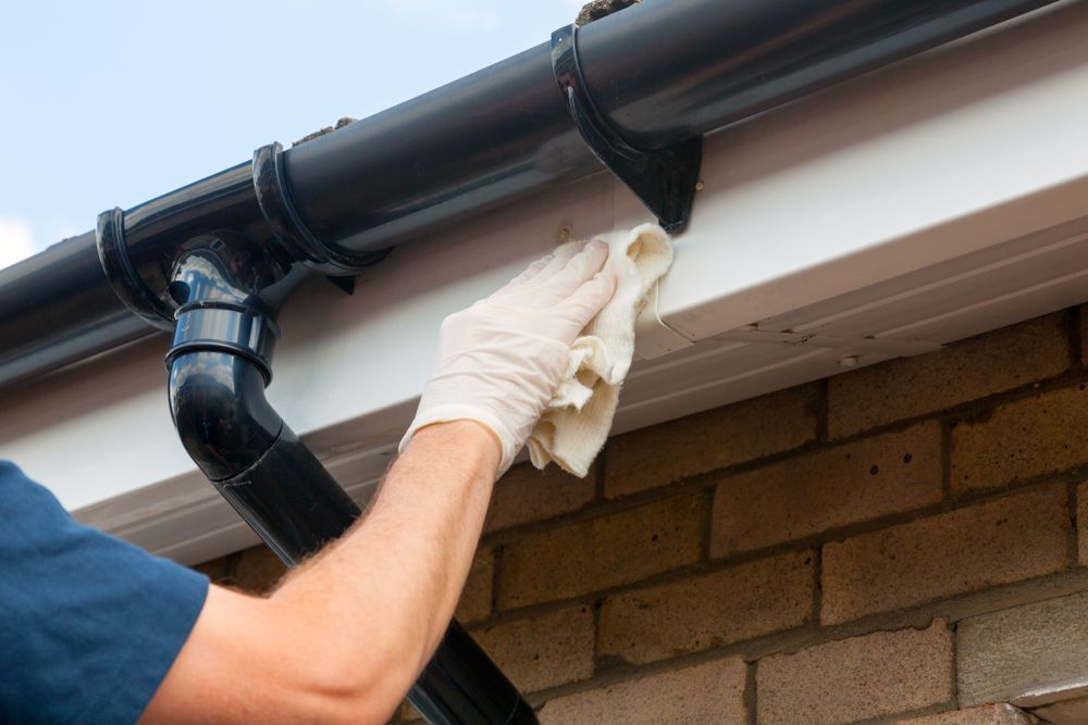 A Dark Gutter and Downspout on A Brick Building — Dunnrite Plumbing Services in Proserpine, QLD