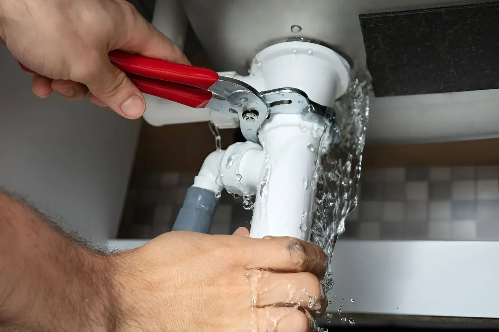 A Plumber Uses Pliers to Tighten a Leaking White Pipe — Dunnrite Plumbing Services in Airlie Beach, QLD