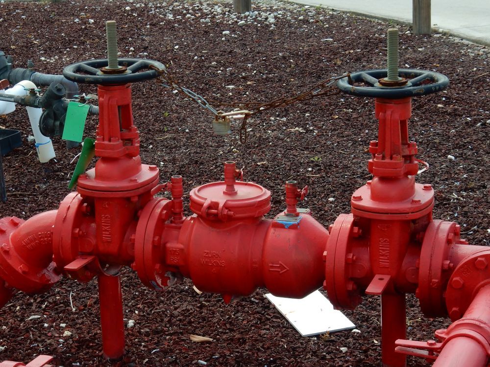 Two Red Industrial Gate Valves Connected to A Central Check Valve — Dunnrite Plumbing Services in Proserpine, QLD