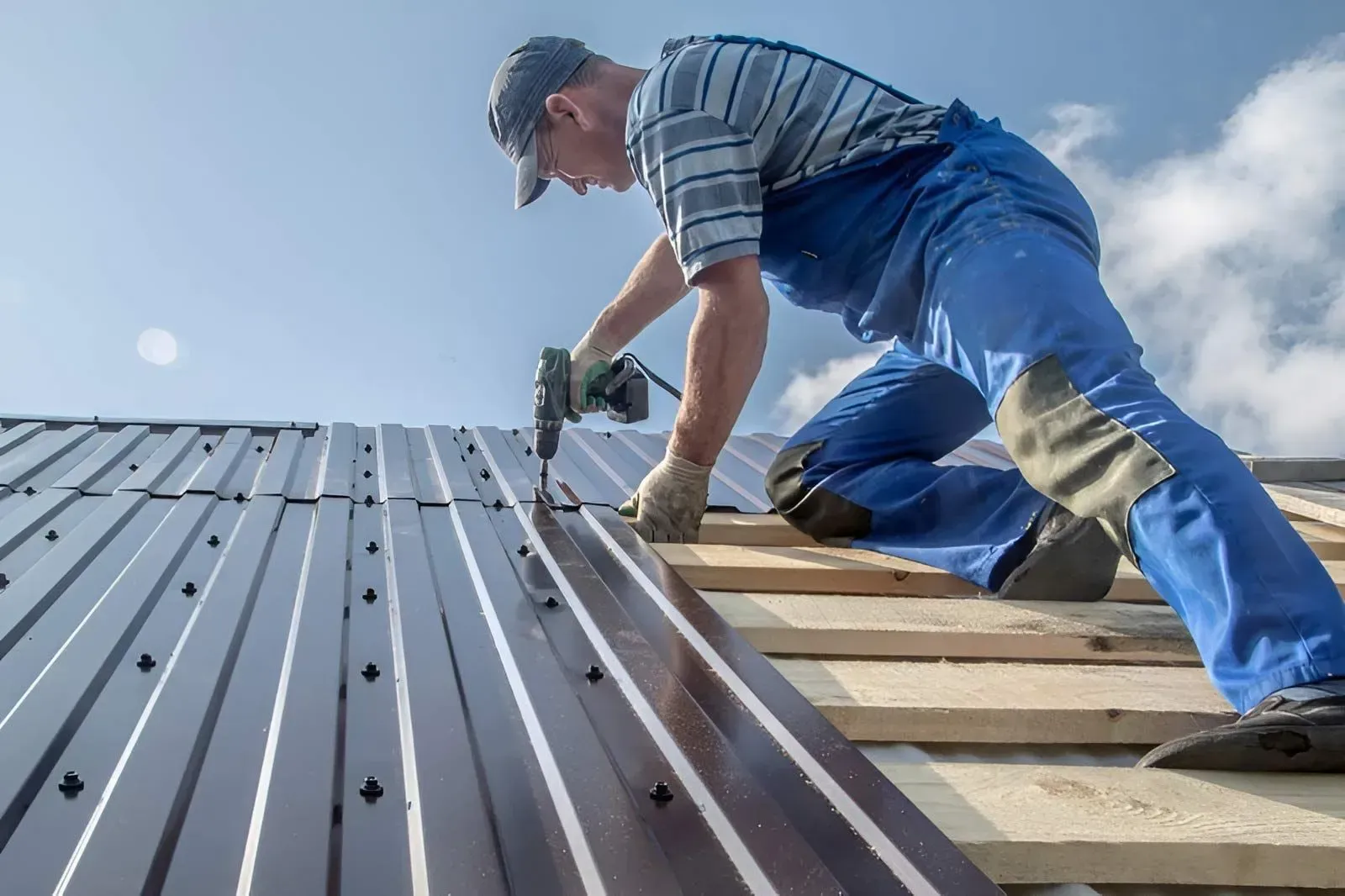 A Worker Using a Power Drill to Fasten Corrugated Roofing Sheets — Dunnrite Plumbing Services in Cannonvale, QLD