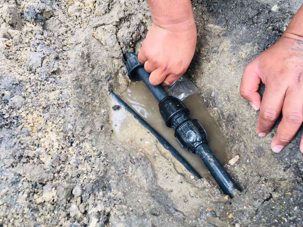 A Pair of Hands Works to Connect Black Polyethylene Piping — Dunnrite Plumbing Services in Airlie Beach, QLD