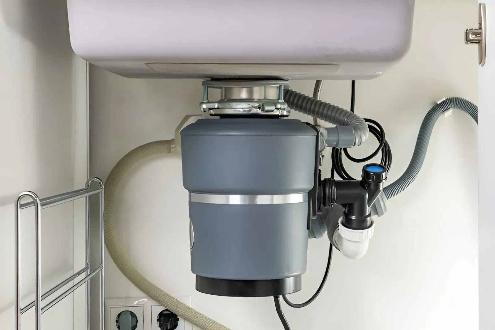 A Gray Garbage Disposal Unit Installed Under a White Kitchen Sink — Dunnrite Plumbing Services in Cannonvale, QLD