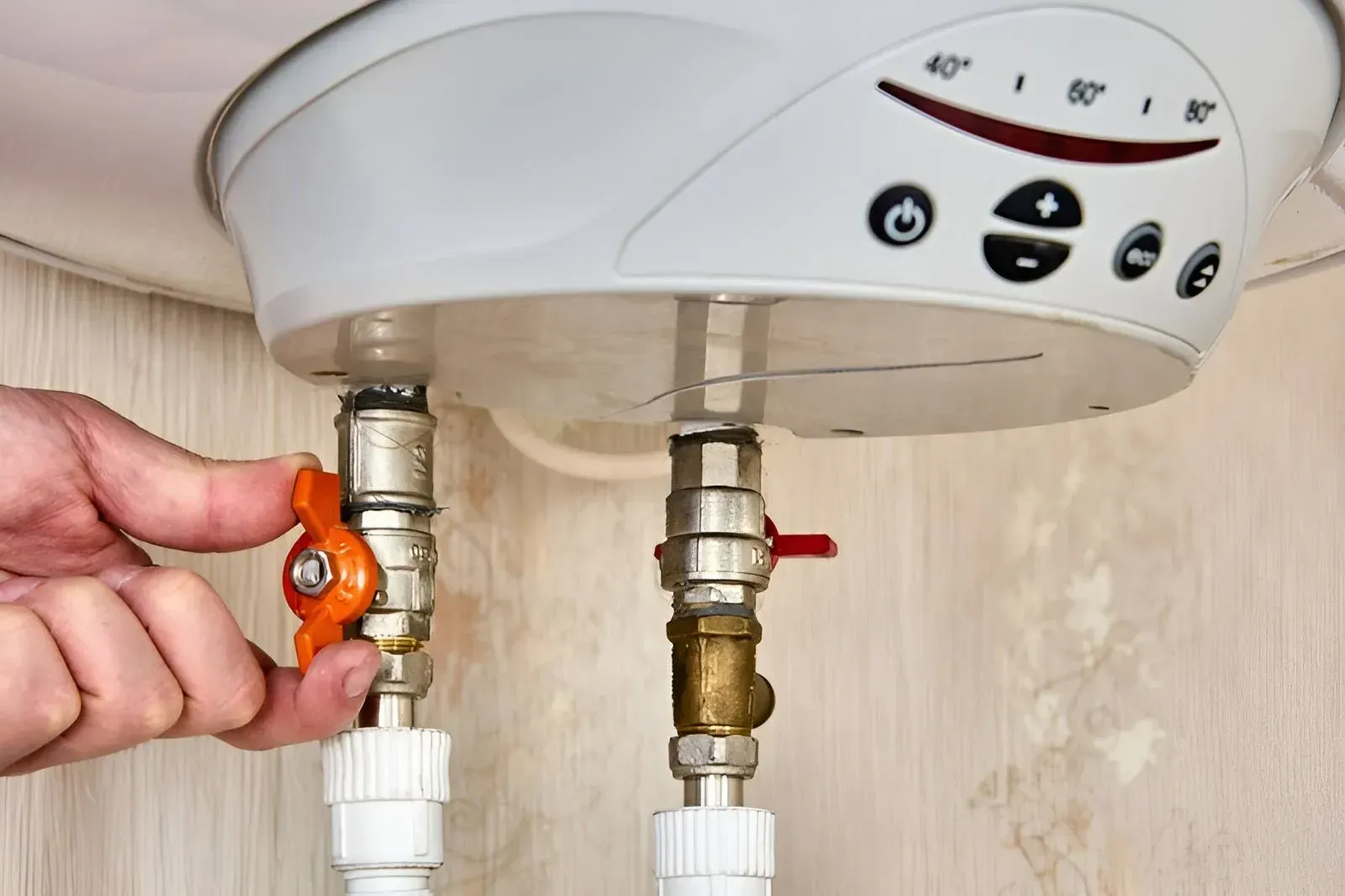 A Hand Turns an Orange Handle on a Metal Valve — Dunnrite Plumbing Services in Airlie Beach, QLD