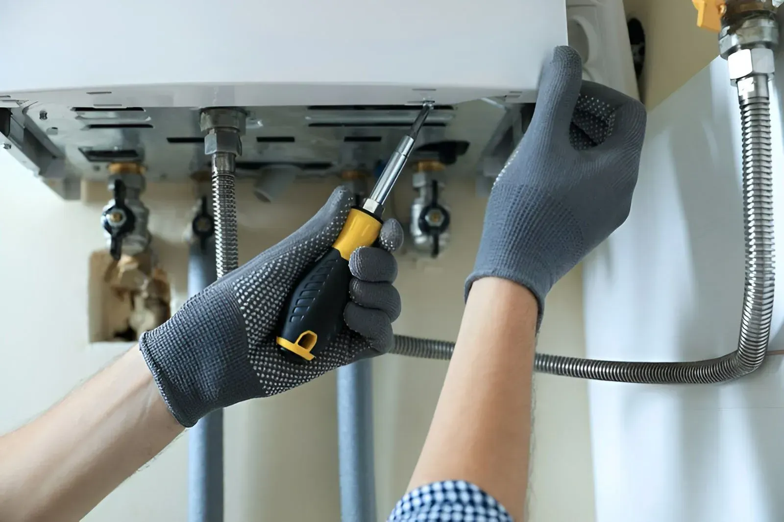 A Person Uses a Screwdriver to Repair or Install Gas Water Heater — Dunnrite Plumbing Services in Airlie Beach, QLD
