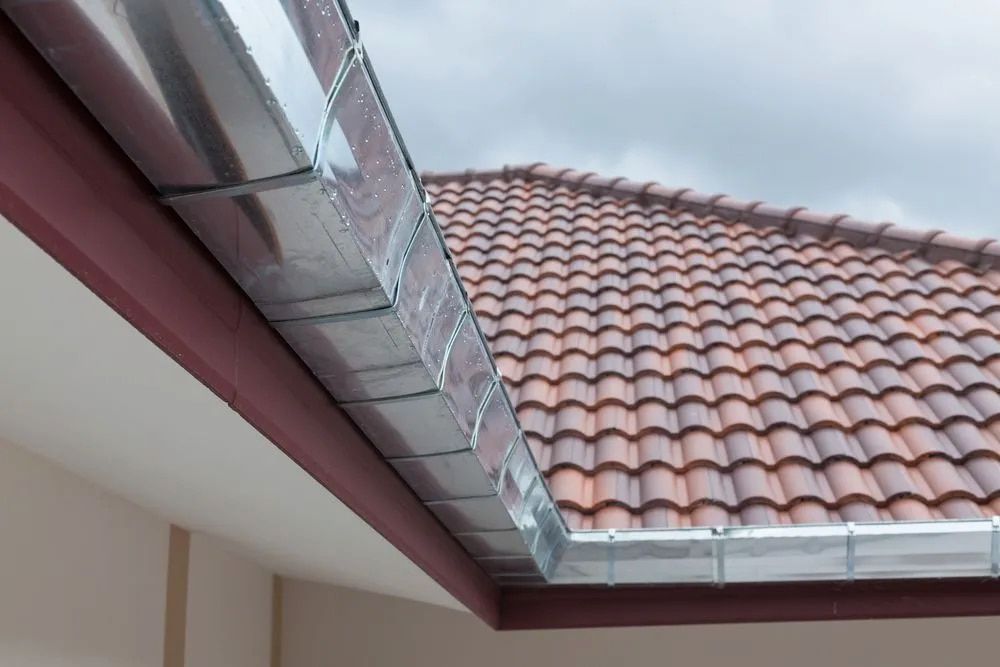 Metal Rain Gutters Installed Along the Edge of a Tiled Roof — Dunnrite Plumbing Services in Proserpine, QLD