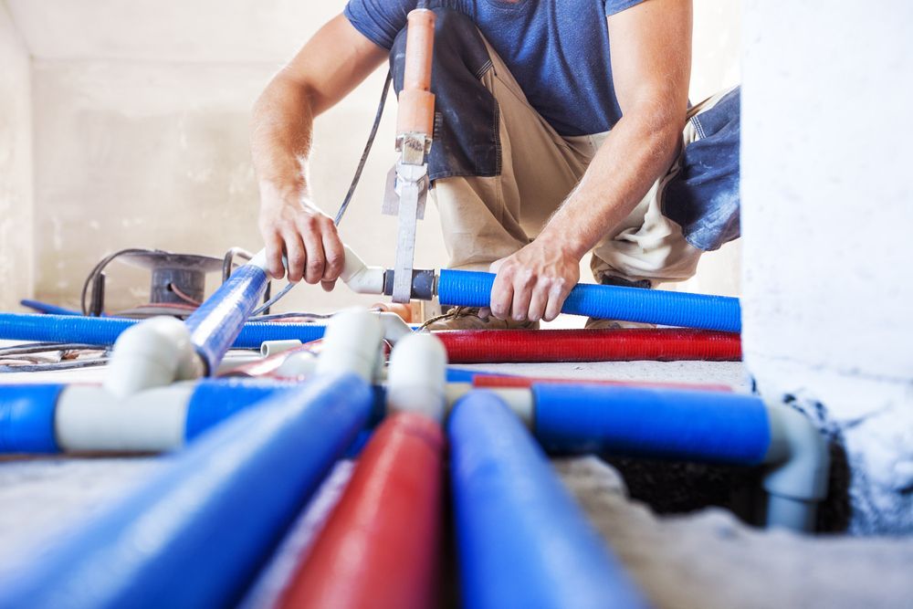A Person Installing Blue and Red Pex Plumbing Pipes — Dunnrite Plumbing Services in Cannonvale, QLD