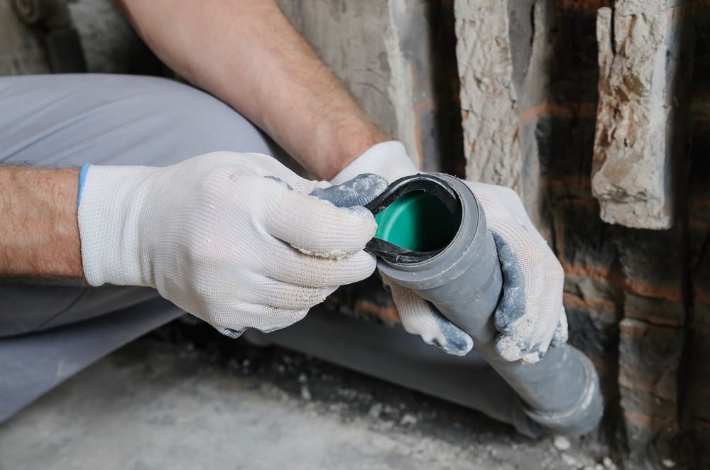 A Worker Wearing White Gloves Inserts a Black Rubber Seal — Dunnrite Plumbing Services in Cannonvale, QLD