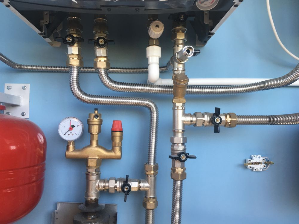 Wall-mounted Gas Boiler Plumbing Setup With Silver Flexible Hoses — Dunnrite Plumbing Services in Proserpine, QLD