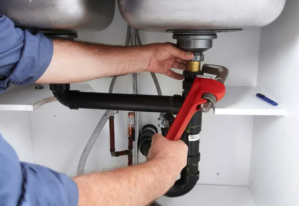 A Person Uses a Red Pipe Wrench to Tighten a Metal Connection — Dunnrite Plumbing Services in Proserpine, QLD