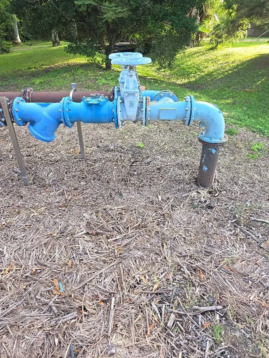 A Blue Metal Gate Valve Attached to Industrial Piping — Dunnrite Plumbing Services in Cannonvale, QLD
